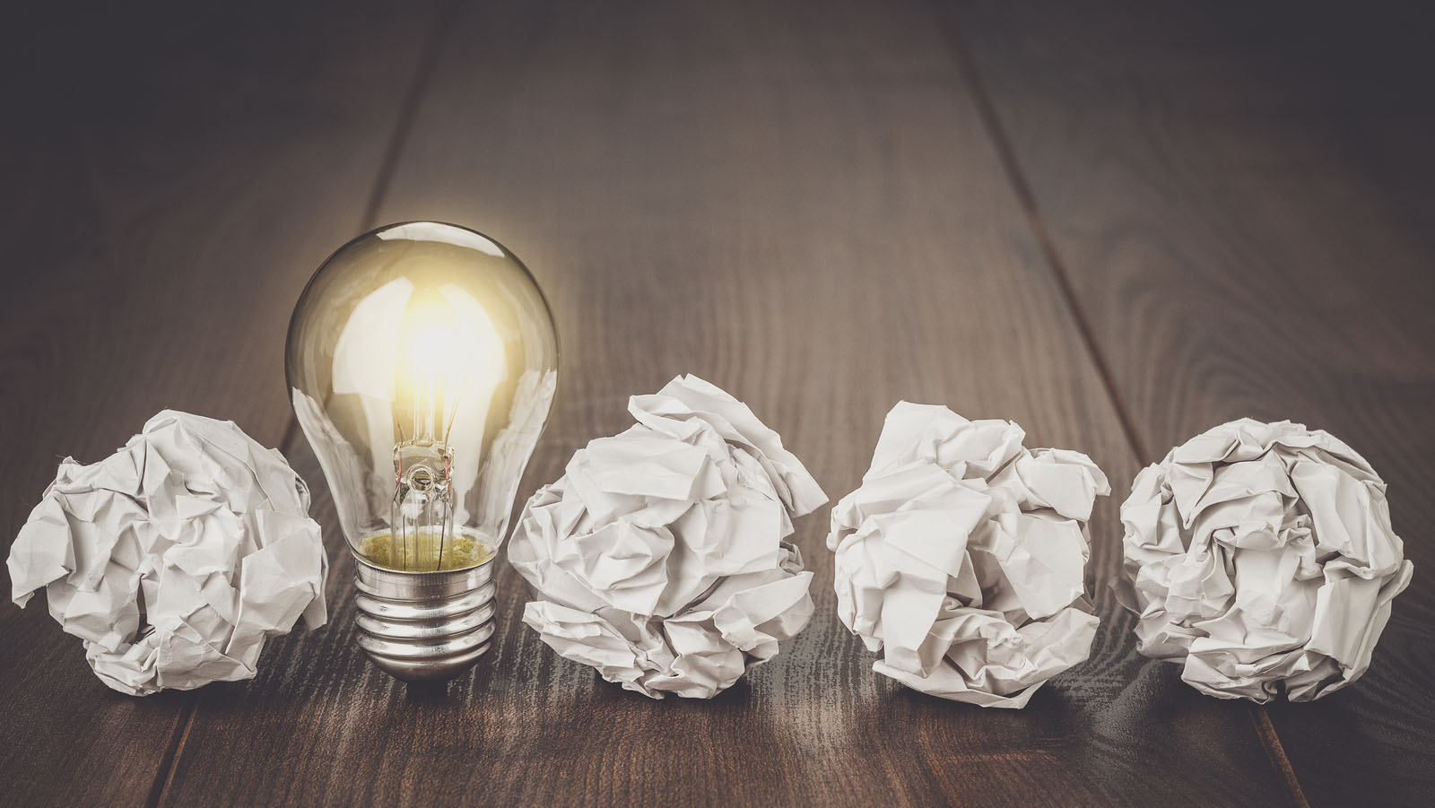 Great idea business concept. Business idea brainstorming concept with crumpled office paper. Great idea as light bulb standing on the office table. Business meeting concept. Business plan idea brainstorming concept.